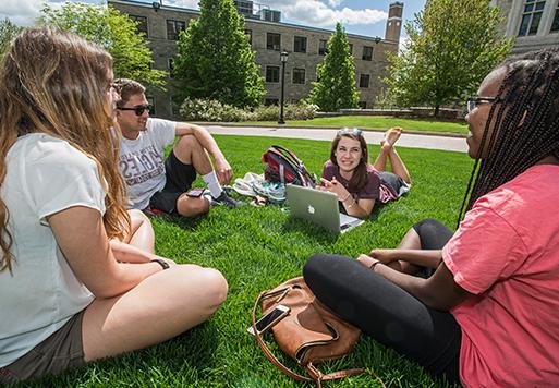 students on a lawn with laptops